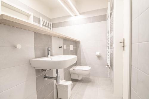 a white bathroom with a sink and a toilet at Garni hotel Roušarka in Sušice