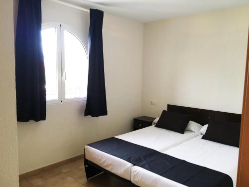 1 dormitorio con 2 camas y ventana en Apartamentos Doña Carmen 3000, en Oropesa del Mar