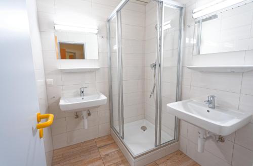 a bathroom with two sinks and a glass shower at Jugend- und Familiengästehaus Klagenfurt in Klagenfurt