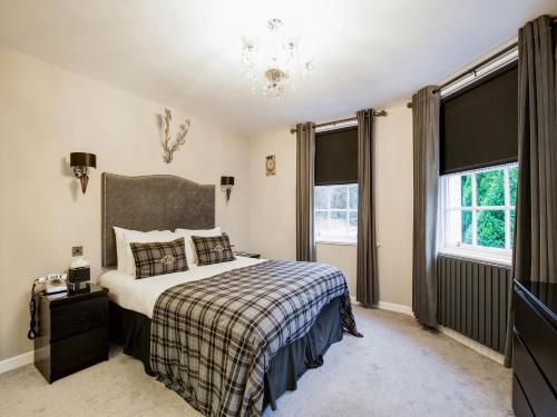 a bedroom with a bed and two windows at Barony Castle Hotel in Peebles