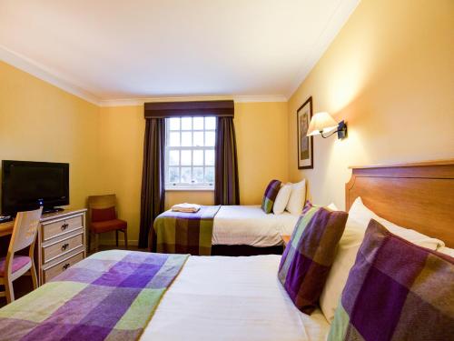 a hotel room with two beds and a television at Barony Castle Hotel in Peebles