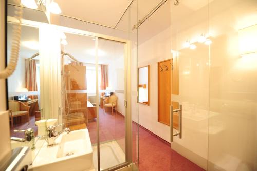 łazienka z przeszkloną kabiną prysznicową i umywalką w obiekcie Hotel Krone w mieście Matrei am Brenner