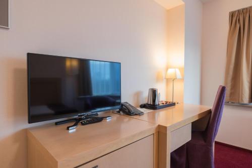 a desk in a hotel room with a large flat screen tv at Riga Islande Hotel with FREE Parking in Rīga
