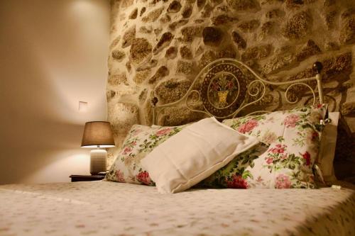 - une chambre avec un mur en pierre et un lit avec des oreillers dans l'établissement Casa da Mina - Eido do Pomar, à Arcos de Valdevez