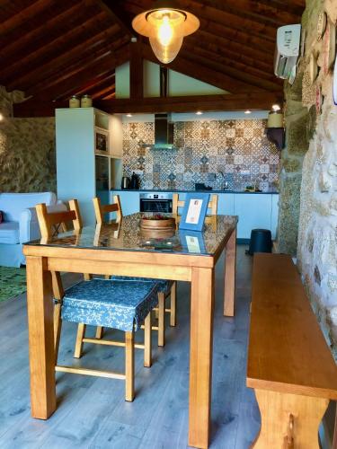 a kitchen with a wooden table with chairs and a counter at Casa da Mina - Eido do Pomar in Arcos de Valdevez