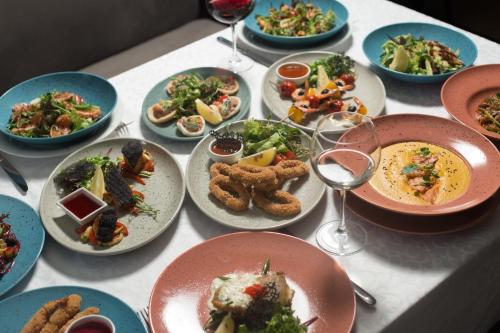 a table with plates of food and glasses of wine at Kolyada Hotel in Odesa