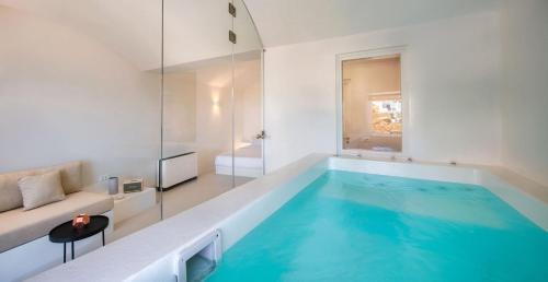 a large swimming pool in a white room with a tub at Old Castle Oia in Oia