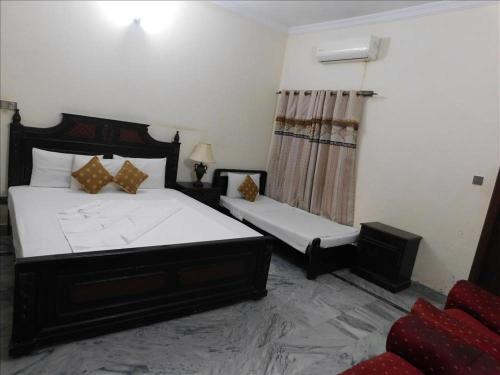 a bedroom with a large bed and a chair at AB Guesthouse in Rawalpindi