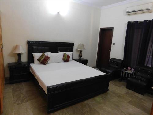 a bedroom with a large bed and two lamps at AB Guesthouse in Rawalpindi