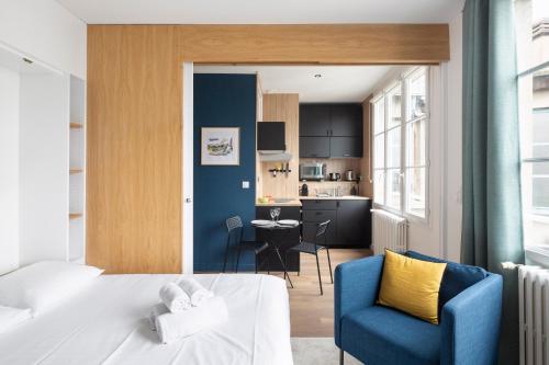 Cet appartement comprend une chambre avec un lit et une chaise bleue ainsi qu'une cuisine. dans l'établissement Le Cinq by Cocoonr, à Nantes