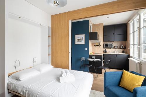 une chambre avec un lit blanc et une chaise bleue dans l'établissement Le Cinq by Cocoonr, à Nantes