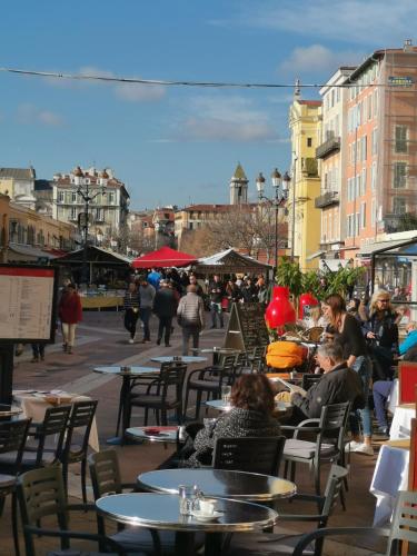 un grupo de personas sentadas en mesas en una ciudad en 2 pièces Vieux-Nice N en Niza