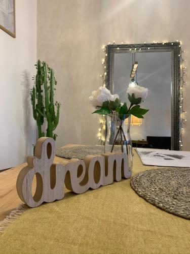 a wooden sign on a table with flowers and a mirror at Villa Inda Rooms in Eger