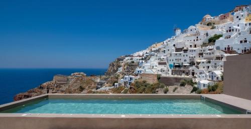 a large building with a pool of water near by at Old Castle Oia in Oia