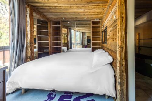 ティーニュにあるChalet Carte Blanche Rock N' Loveの白いベッドと木製の壁が備わるベッドルーム1室が備わります。