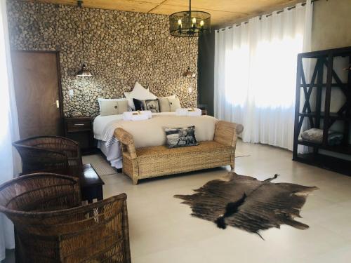 ein Schlafzimmer mit einem Bett, einem Stuhl und einem Sofa in der Unterkunft Burgsdorf Guest Farm in Maltahöhe