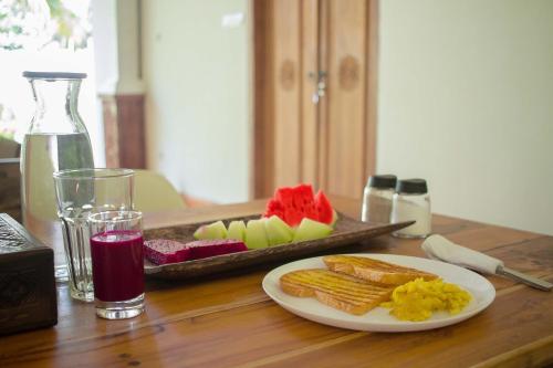 a table with a plate of food and a tray of fruit at Adara Homestay in Banyuwangi