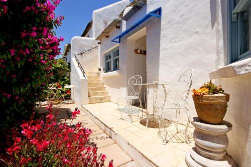 a patio with chairs and flowers in front of a house at Gilcrest Place Guest House in Paternoster