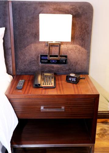 a bedside table with a phone and a lamp on it at Indigo Heights Hotel & Suites in Lahore