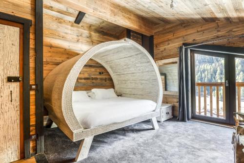 Ce lit se trouve dans un dortoir doté d'un mur en bois. dans l'établissement Chalet Carte Blanche Ubud, à Tignes