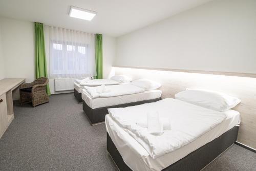 Habitación hospitalaria con 3 camas y escritorio en Garni hotel Roušarka, en Sušice