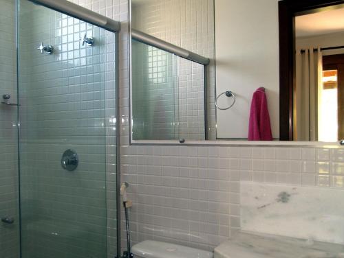 a bathroom with a shower and a toilet and a mirror at RESERVA IMBASSAI - APARTAMENTO TD 17 202 BUGANVILIAS in Imbassai