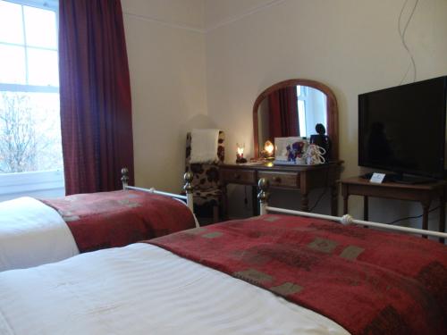 a hotel room with two beds and a mirror at Llanwrtyd Hall B&B Angelis Holistic Retreat in Llanwrtyd Wells