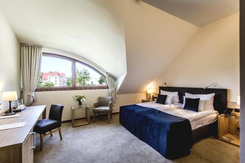a bedroom with a bed and a desk and a window at Uroczysko Siedmiu Stawów Spa by L'Occitane in Gola Dzierżoniowska