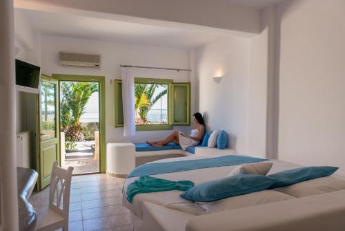 a woman sitting in a room with two beds at Aelia by Eltheon in Imerovigli