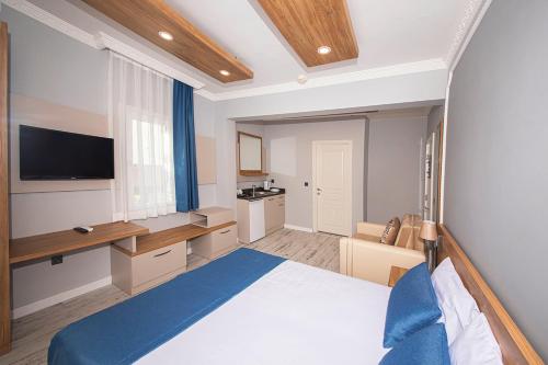 a bedroom with a bed and a desk and a tv at Marina Hotel Bodrum in Bodrum City