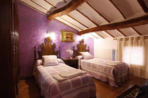 two beds in a room with purple walls at Casa Victoria in Cirueña