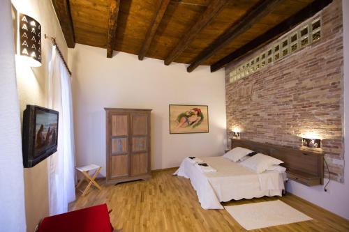 1 dormitorio con cama y pared de ladrillo en Castelletto Suites, en Cagliari