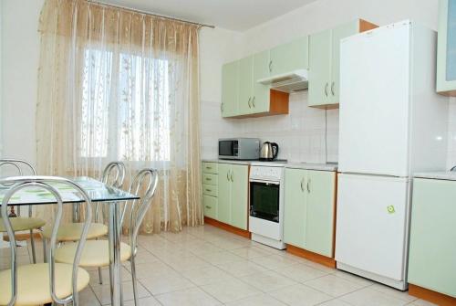 キーウにある2-komnatnye apartamenty Alladin - Pozniakiのキッチン(白い家電製品、テーブル、椅子付)