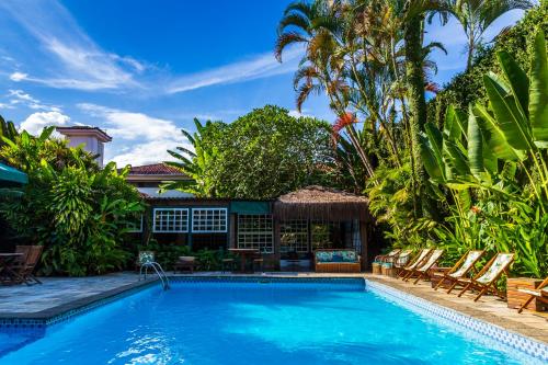 a swimming pool with chairs and a house at Pousada do Príncipe in Paraty