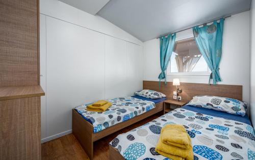 1 dormitorio con 2 camas y ventana en Panorama Mobile Homes in Camping Park Umag en Umag