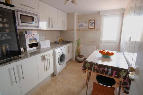 una cocina con armarios blancos y una mesa con un bol de fruta en Casa Victoria, en Cirueña