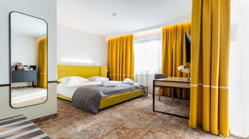 a bedroom with yellow curtains and a bed and a mirror at Qubus Hotel Kraków in Krakow