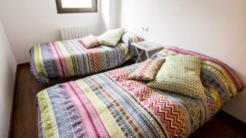 two beds with colorful blankets and pillows in a room at Casa Rural Galana in La Puebla de Valverde