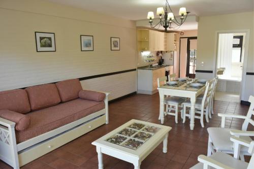 sala de estar con sofá, mesa y cocina en Apart Hotel Las Hadas Carilo en Cariló