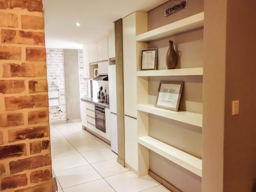 a kitchen with white tile floors and shelves at Elegant Apartment at Grove Mall in Windhoek