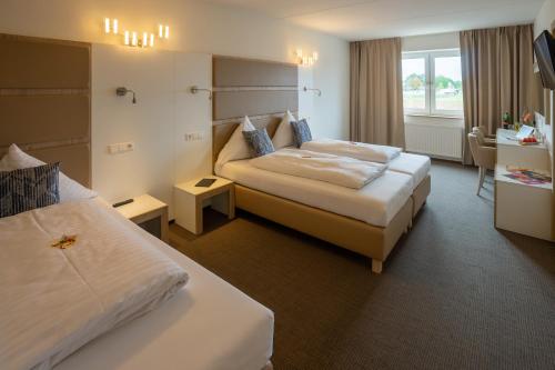 ein Hotelzimmer mit zwei Betten und einem Fernseher in der Unterkunft Confour Hotel in Burgdorf