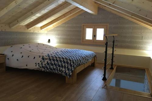 ein Schlafzimmer mit einem Bett in einer Holzhütte in der Unterkunft Les Maisons de la Glappaz in Mégevette