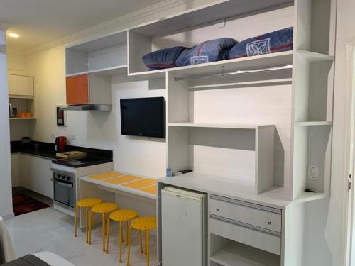 uma cozinha com armários brancos e bancos amarelos em FLAT AMARÍLIS - RIVIERA DE SÃO LOURENÇo em Riviera de São Lourenço