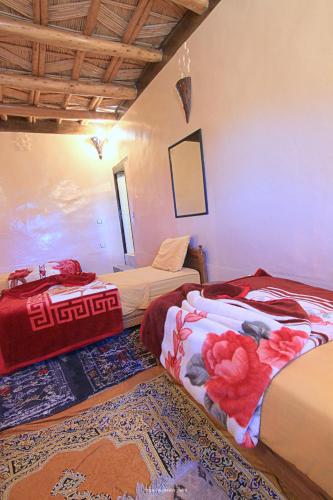 a bedroom with two beds and a rug at Tigmi Tachddirt in Tacheddirt