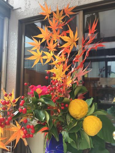 a blue vase filled with orange flowers and fruit at Guest house daisho oshiro asobi in Matsue
