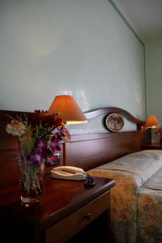 un tavolo con una lampada e un vaso di fiori su un letto di Hotel Bracco a Loreggia