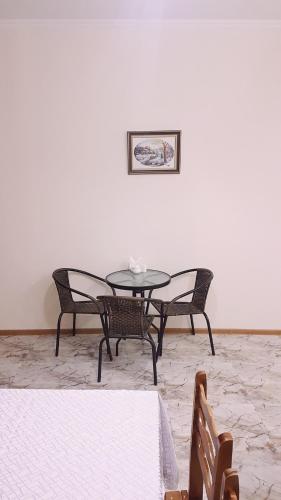 einen Tisch und Stühle in einem Zimmer mit einer weißen Wand in der Unterkunft Guest house Jangulashvili in Sighnaghi