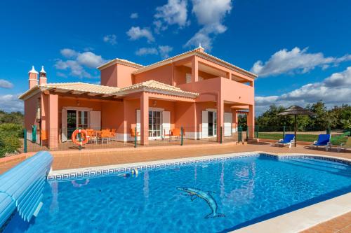 a villa with a swimming pool in front of a house at Villa da Horta in Alcantarilha
