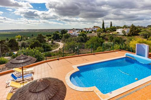 a swimming pool with umbrellas and a view of a villa at Villa da Horta in Alcantarilha