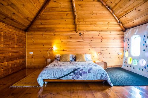 ein Schlafzimmer mit einem Bett in einer Holzhütte in der Unterkunft Casa Inspirada in Los Estancos